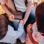 A group of children enjoying applying temporary tattoos together outdoors.