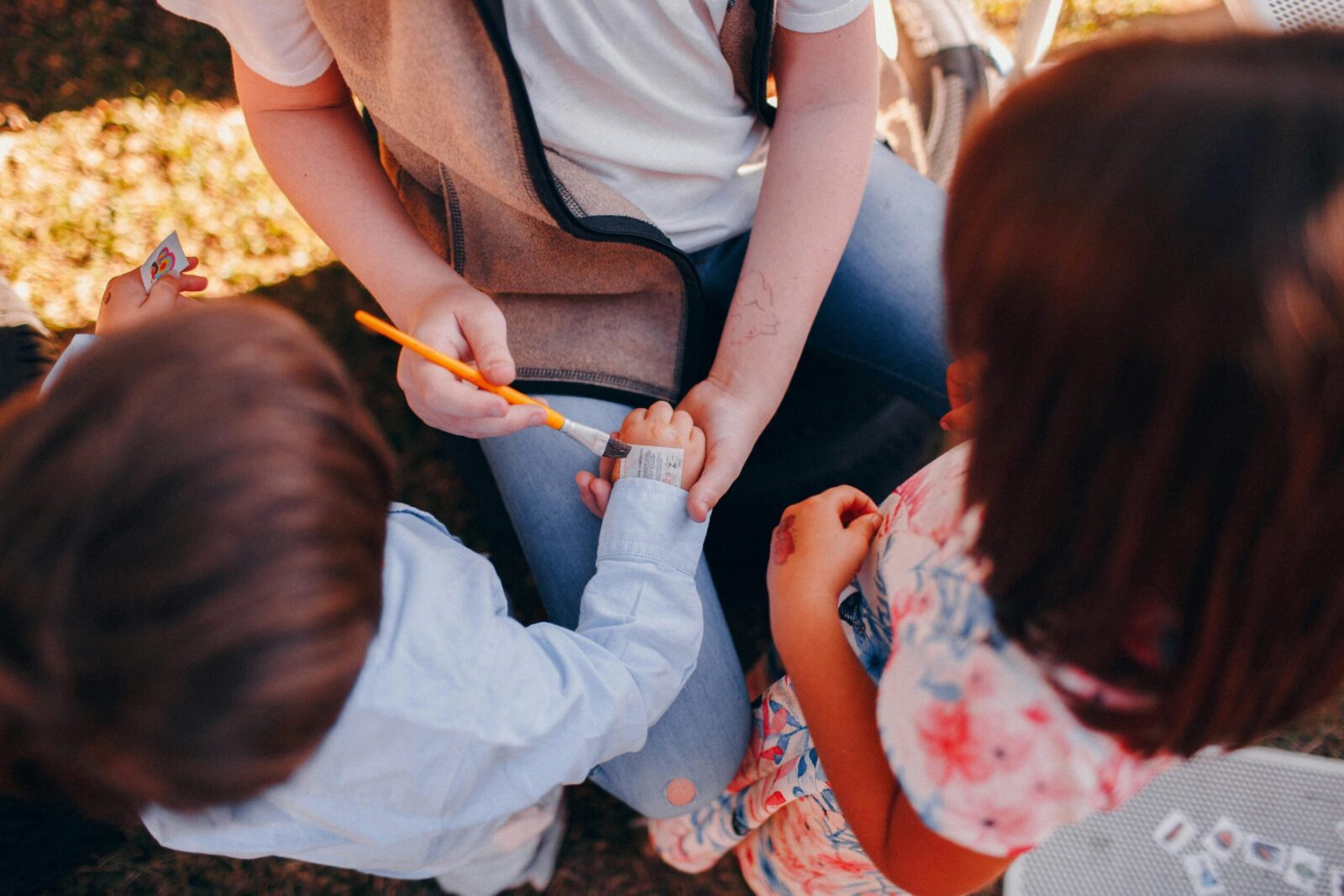 A group of children enjoying applying temporary tattoos together outdoors.