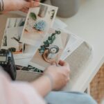 From above anonymous photographer looking through printed photos placed on white table in living room