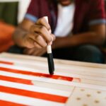 Child painting an American flag as a creative school project with foam brush.
