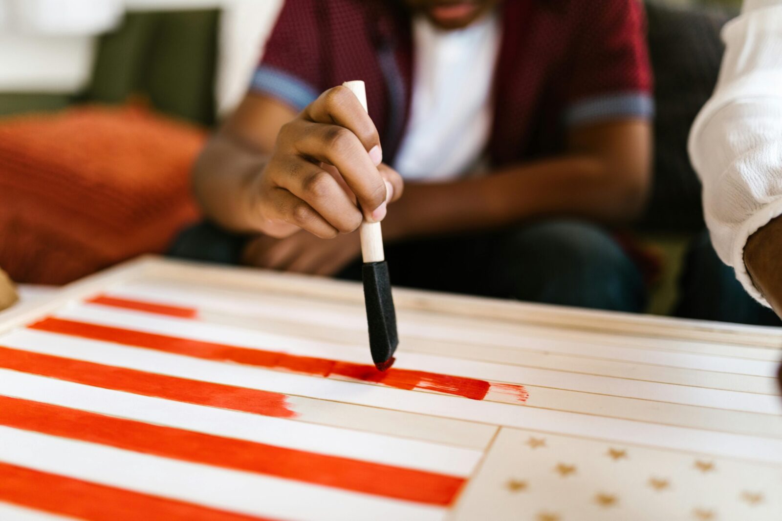 Child painting an American flag as a creative school project with foam brush.