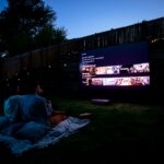 Two people sitting on a blanket watching a movie